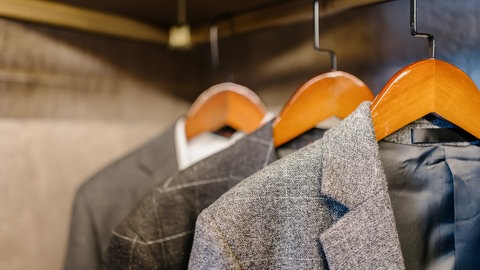 Sakkos auf Kleiderbügeln im Kleiderschrank