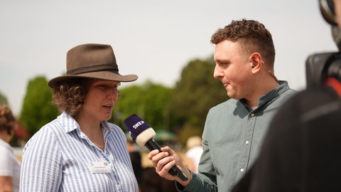 Ein Reporter interviewt eine Frau mit Cowboyhut.