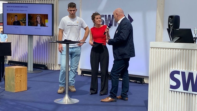Zwei Handwerker stehen mit Moderatorin auf der Bühne