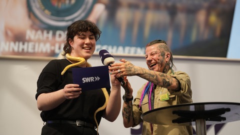 Reporterin Mailin Engels mit einer Schlange auf der Bühne.