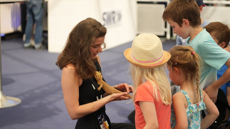 Kindermagnet Bartagame: SWR Moderatorin Klara Hofmann umringt von jungen Maimarkt-Besuchern.