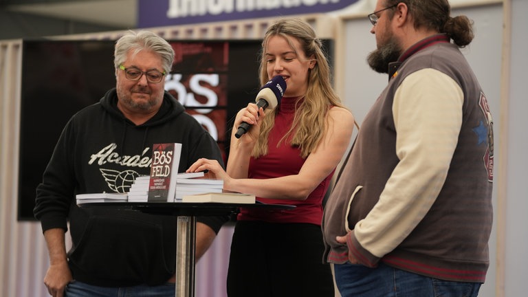 Auf der SWR-Bühne: Krimi-Autoren Klaus Maria Dechant und Christian Hofbauer des Maimarkt-Krimis Bösfeld im Gespräch mit Judith Hofbauer.