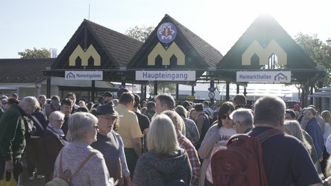 Mehrere hundert Menschen warten auf den Einlass vor dem Maimarkt-Gelände.