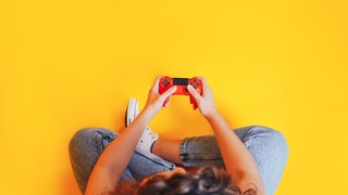 Eine Person mit einem Gaming-Controller von oben fotografiert.