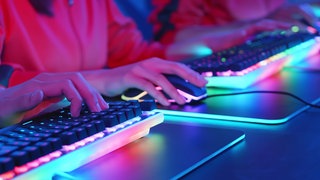 Beleuchtete Computer-Tastaturen & -Mäuse mit Hände, die diese bedienen.