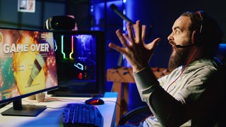 Gamer regt sich vor seinem PC auf.