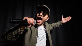 Ein Rapper mit Mikrofon in der Hand.