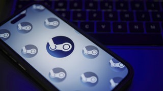 Das Steam-Logo auf einem Smartphone. Im Hintergrund eine Tastatur.