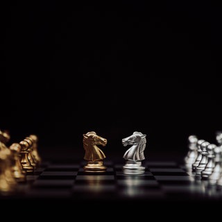 Ein Schachbrett mit silbernen und goldenen Schachfiguren.