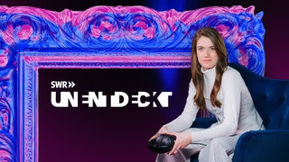 Sissy Hertneck sitzt mit Kopfhörer vor einem großen Bilderrahmen auf dunklem Hintergrund