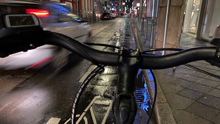 Ein Auto fährt sehr dicht an einem Radfahrer vorbei.
