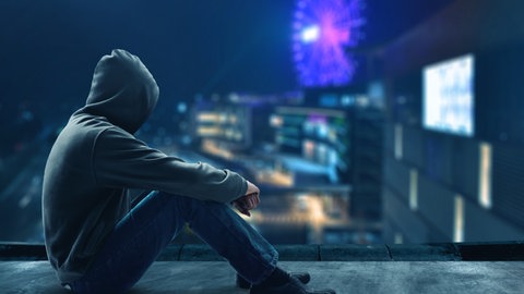 Eine Person alleine im Dunkeln, Lichter einer Stadt im Hintergrund. Bild: iStockFOTOKITA