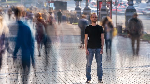 Verschwommen sind Menschen und Umgebung um einen Mann herum. Bild: iStockViacheslav Peretiatko
