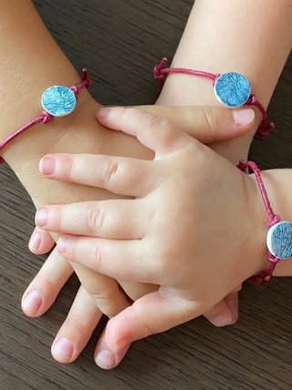Das sind die Hände von drei "großen" Schwestern. Sie tragen Armbänder mit den Fingerabdrücken ihres kleinen Bruders. Er wurde nur 15 Tage alt. 