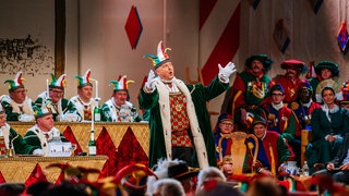 Ein Mann des Stockacher Narrengerichts hält einen Vortrag in Narrenmütze und grünem Mantel. Es ist eine beliebte Sitzung an Fastnacht.