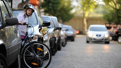 Mädchen, 8 Jahre, mit dem Fahrrad im Straßenverkehr einer Wohnstraße in Düsseldorf, Nordrhein-Westfalen