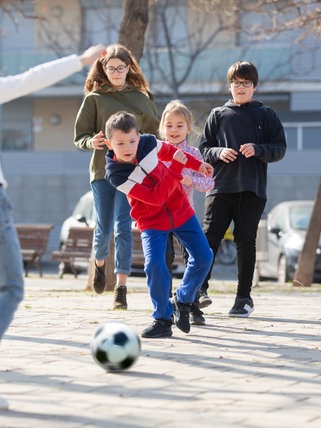  Kinder spielen Fußball auf der Straße