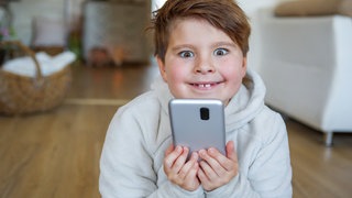 Beispielbild für: Eine Junge freut sich über sein erstes Smartphone.