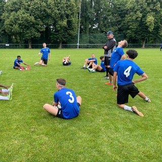 Fußballer dehnen sich auf einem Platz in Karlsruhe.