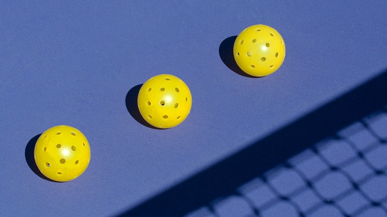 Pickleball Bälle nebeneinander auf einem Feld.