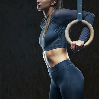 Beschnittenes Porträt einer jungen Sportlerin mit Gymnastikringen im Fitnessstudio