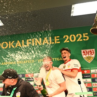 Stuttgarts Trainer Sebastian Hoeneß (vorn) wird auf der Pressekonferenz nach dem Pokalsieg von seinen Spielern mit Bier begossen