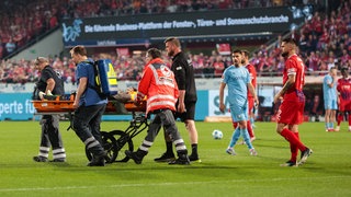 Heidenheims Keeper Kevin Müller wird aus dem Stadion transportiert