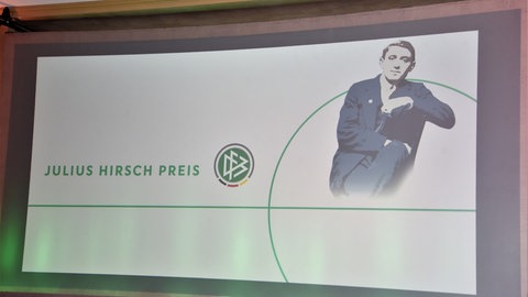 Eine Powerpoint-Folie mit einem Bild von Julius Hirsch und dem DFB-Logo wird mit einem Projektor an eine Wand geworfen