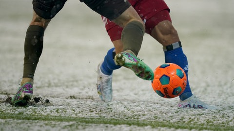 Zwei Fußballer kämpfen im Schnee um den Ball.