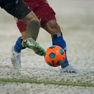 Zwei Fußballer kämpfen im Schnee um den Ball.