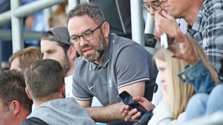 Marc Strauß, der zukünftig für den FCK tätig sein wird, sitzt auf der Tribüne eines Stadions.