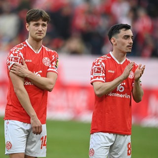 Die Mainzer William Bøving und Paul Nebel stehen mit hängenden Köpfen vor der Fankurve. Sie ärgern sich über den vergebenen Sieg gegen de VfB Stuttgart.