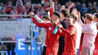 Spieler des 1. FC Heidenheim feiern nach dem Sieg gegen Union Berlin mit den Fans.