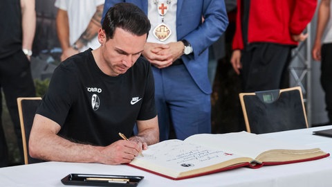Nicolas Höfler (SC Freiburg) trägt sich ins goldene Buch der Stadt Freiburg ein