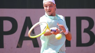 Jan-Lennard Struff schlägt beim Spiel mit dem Schläger gegen den Tennisball.