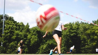 Ein Faustball fliegt auf einem Spielfeld über die Leine zu Boden.