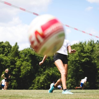 Ein Faustball fliegt auf einem Spielfeld über die Leine zu Boden.