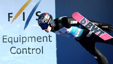 Fotomontage: Skispringer Marius Lindvik (Norwegen), welcher wegen eines Skandals Diqualifiziert wurde. Im Hintergrund ein Schild der FIS: "Equipment Control".