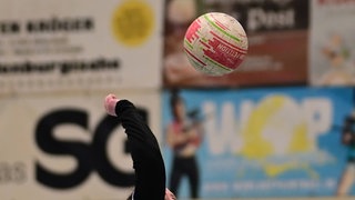Bei einem Faustball-Spiel wird eine zur Faust geballte Hand Richtung Ball bewegt.
