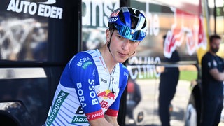 Florian Lipowitz vor dem Start einer Etappe der Tour de Romandie vor dem Teambus.