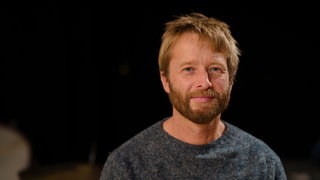 Mann mit Bart schaut frontal in Kamera