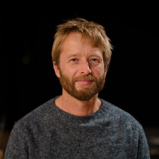 Mann mit Bart schaut frontal in Kamera