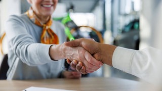 Ältere Frau schüttelt einem Mann die Hand