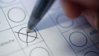 Eine Person macht ein Kreuz auf einem Wahlzettel.