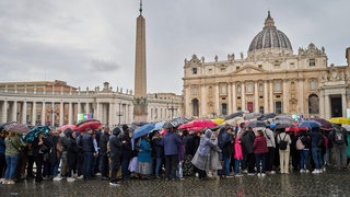 Gläubige warten im Regen in einer Schlange, um dem aufgebahrten Papst Franziskus im Petersdom die letzte Ehre zu erweisen