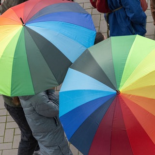 Aufgespannte Regenschirme in Regenbogenfarben. Ab Samstagabend soll in Rheinland-Pfalz Regen fallen.