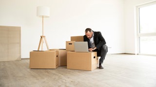 Businessman using laptop on cardboard box while working from new home