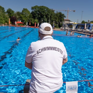 Ein Schwimmmeister überwacht das Treiben im Freibad.
