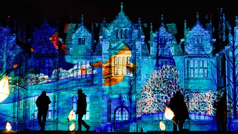 Besucher betrachten eine Projektion auf das Herrenhaus in Wakehurst während des "Glow Wild" Festivals im botanischen Garten Kew Gardens in West Sussex