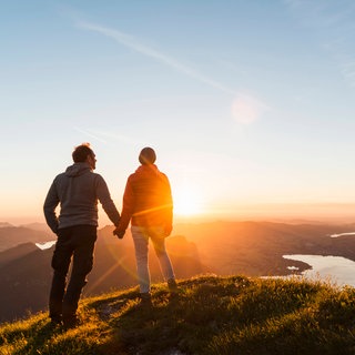 Paar hält Händchen auf Berggipfel. Richtig streiten kann man lernen.